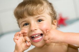 A little girl flossing her teeth