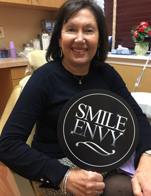 patient holding up new smile new style sign