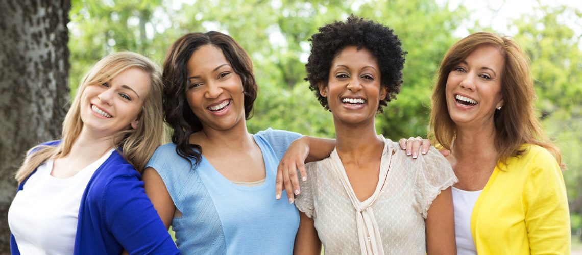 group of four diverse women smiling together